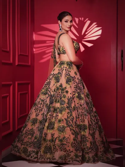 A full-length back view showcasing the beautiful flare of the lehenga and the sheer dupatta. The hairstyle is a clean, elegant bun to keep the focus on the outfit.