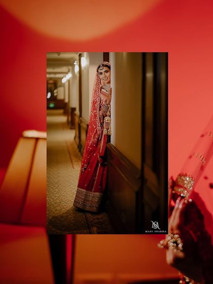 A creative bridal portrait, with the bride peeking out from a corner in a hotel corridor. The framing and warm lighting add an artistic and intimate touch.