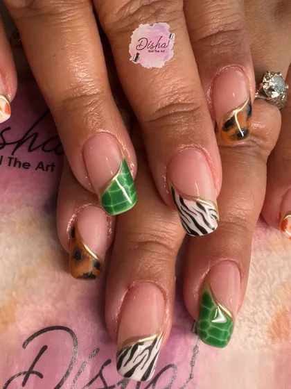 Taking it wild with these animal print French tips. Each nail features a different pattern, from leopard and giraffe to zebra and crocodile, all with a fine gold border.