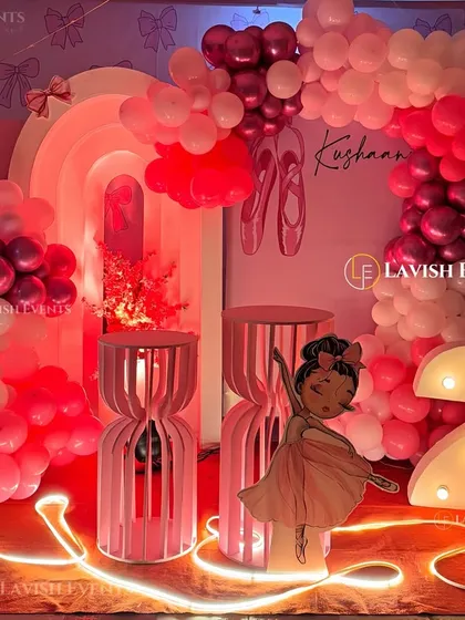 A graceful ballerina-themed party in shades of pink and red, featuring a large cutout of a dancer, a light-up number '2', and elegant decor elements.