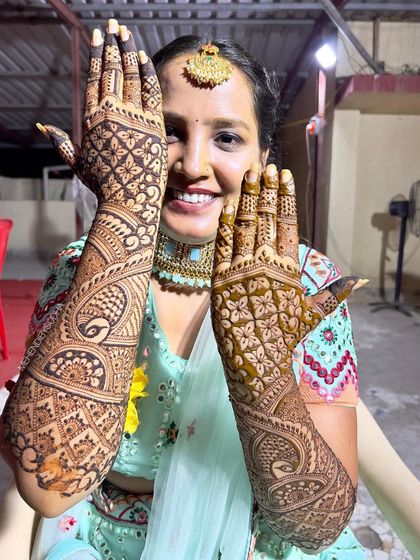 A happy bride showing off the back of her hands, with symmetrical designs that are both elegant and traditional.