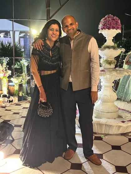 Attending a wedding with my husband. For the celebration night, I'm wearing a custom black lehenga with a cape, and he is in a classic waistcoat, showing how a couple can coordinate in style.