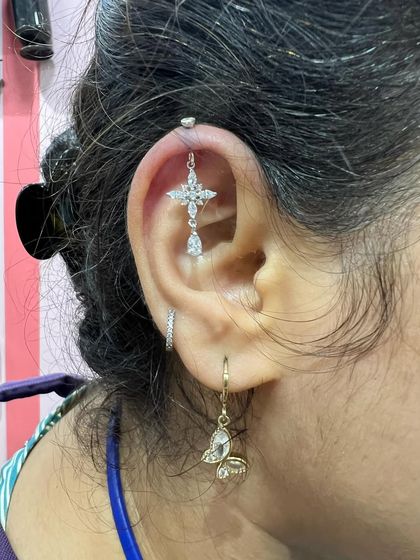 A cross-shaped hanging with a teardrop diamond, paired with a butterfly hoop.