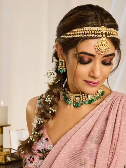 A bohemian-inspired bridal braid. This loose, textured braid is woven with baby's breath and paired with a sheeshpatti for a look that is perfect for a Mehendi or a relaxed outdoor wedding.
