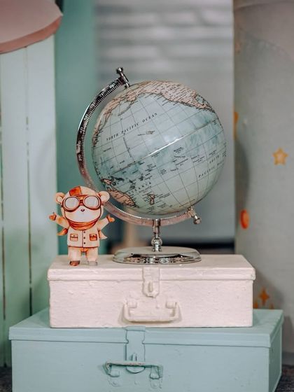 A charming detail from our travel theme: a vintage globe and suitcases with a little explorer character.