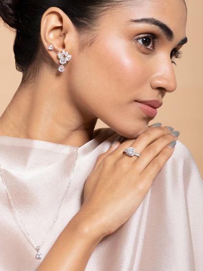A classic profile shot perfect for showcasing earrings and rings. The clean lighting highlights the sparkle of the diamond-simulant stones without creating harsh reflections. The model's elegant pose and neutral styling keep the focus entirely on the jewelry.