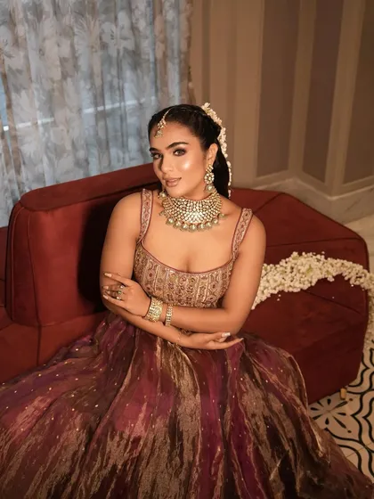 A complete look at this stunning bridal Mehendi style. The rich, multi-toned lehenga was paired with a glamorous makeup look featuring a shimmery eye, glowing skin, and a beautiful long ponytail adorned with mogra flowers.