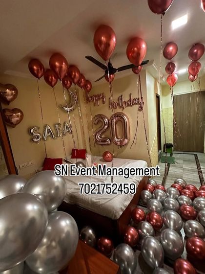 A romantic birthday room decoration with rose gold and silver balloons. The setup includes foil letters for the name and age, creating a personalized surprise.