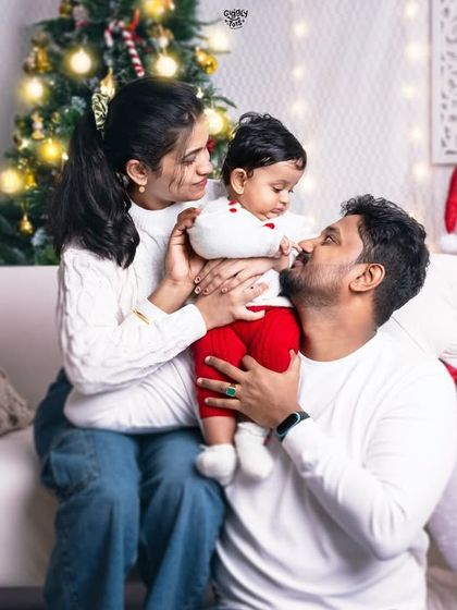 A sweet, candid moment between parents and their baby, surrounded by the magic of Christmas. The snowman and festive lights add a touch of wonder to this family's first holiday portrait.