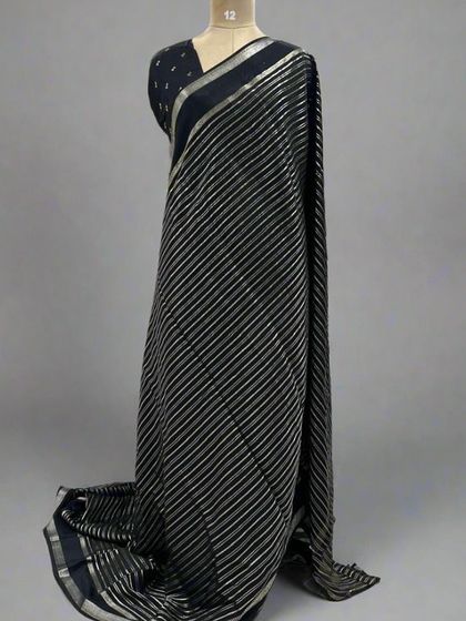 A mannequin draped in a classic black saree with silver stripes.