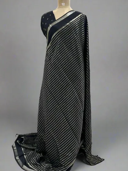 A mannequin draped in a classic black saree with silver stripes.