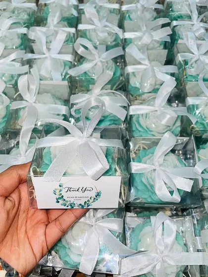 A beautiful order of rose-shaped candles in a fresh mint green and white, packaged with personalized tags for a wedding.