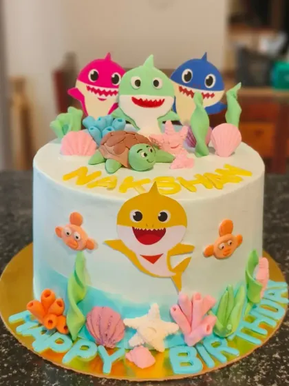 An adorable Baby Shark cake featuring fondant sea creatures and the whole shark family. The light blue ombre effect mimics the ocean.