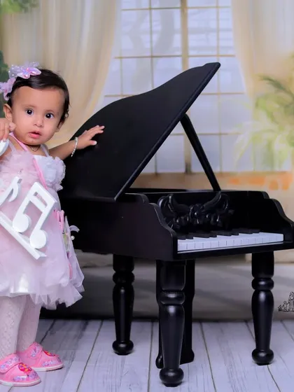 Holding the music in her hands. This creative pose with the musical note prop adds a unique and artistic element to the baby's portrait.