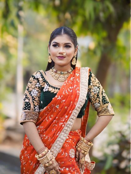 A beautiful model in a modern Nauvari look. The orange saree is paired with a contrasting embroidered green blouse for a contemporary twist.