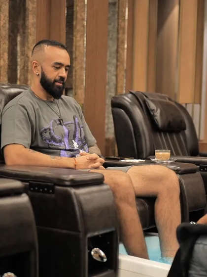 Men's self-care is just as important. Here, a client relaxes with a cup of tea while enjoying a therapeutic foot soak as part of his pedicure.