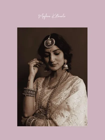 A sepia-toned portrait that enhances the vintage feel of the styling. The focus is on the intricate details of the jewelry, from the maang tikka to the stacked bangles, and the bride's serene expression.