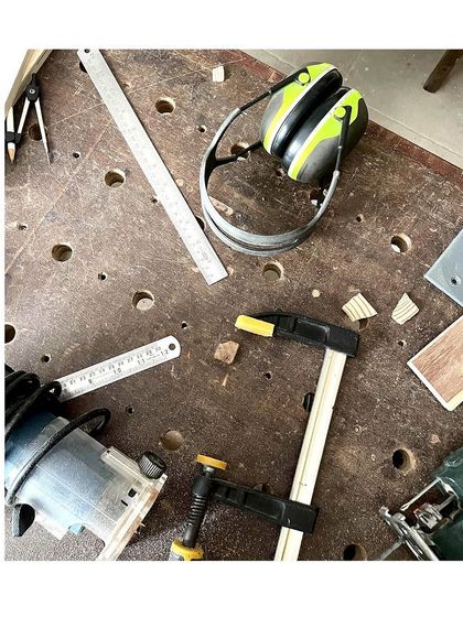 A typical scene on my workbench. You can see a router, clamps, measuring tools, and safety earmuffs. These are the essential tools of the trade.