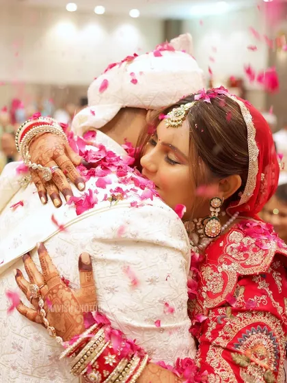 A close-up of an emotional hug between the bride and groom, with flower petals showering down on them.