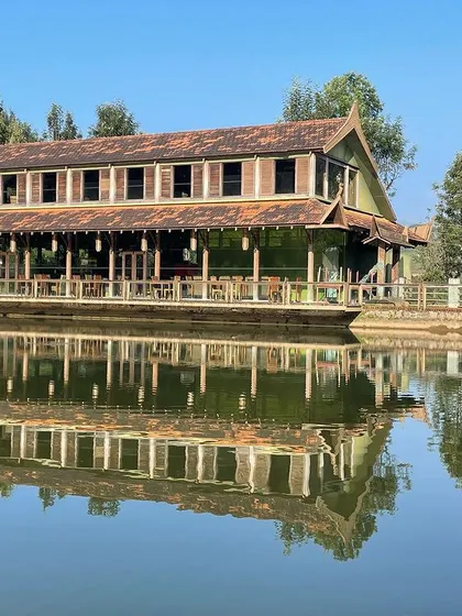 The ODEA Riverside Retreat in Kotagiri, perfectly reflected in the water it overlooks. The design uses a modular steel structure and reclaimed wood, creating a sustainable building that appears to float on the lake.