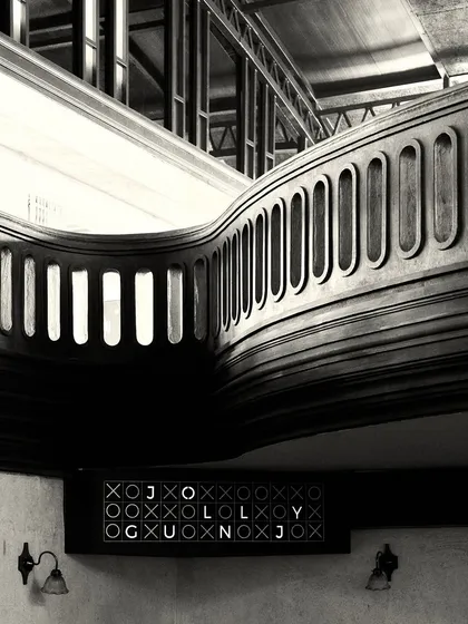 Another view of the flowing balcony railing and the custom signage. The contrast between the dark wood and the light walls is a key visual theme.