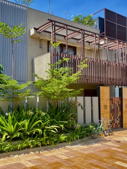 A view of the Udyāna multi-dwelling units, where modern architectural forms are softened by lush, integrated landscaping. The design focuses on creating a seamless transition between the built environment and the natural elements.
