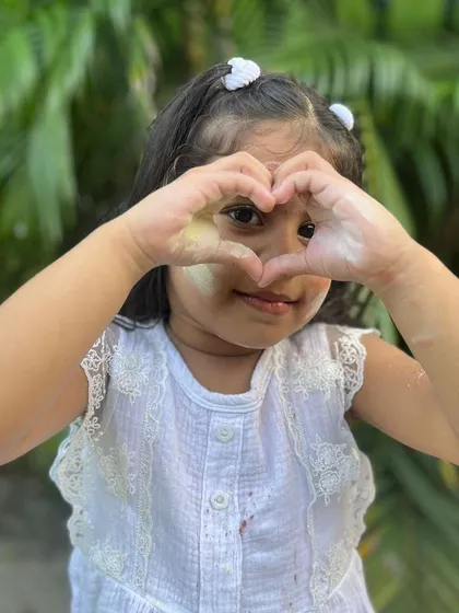 (Duplicate of 54) Making a heart shape with her hands, covered in my gentle Holi colours. It warms my heart to see children enjoying my products safely.
