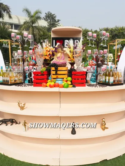 A creatively designed bar for the Banaras event, featuring a tiered structure and decorated with fruits, flowers, and unique figurines.