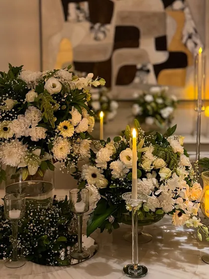 A close up of the candlelit tablescape. The combination of tall and short candles with lush white floral arrangements creates a dynamic and glowing centerpiece.
