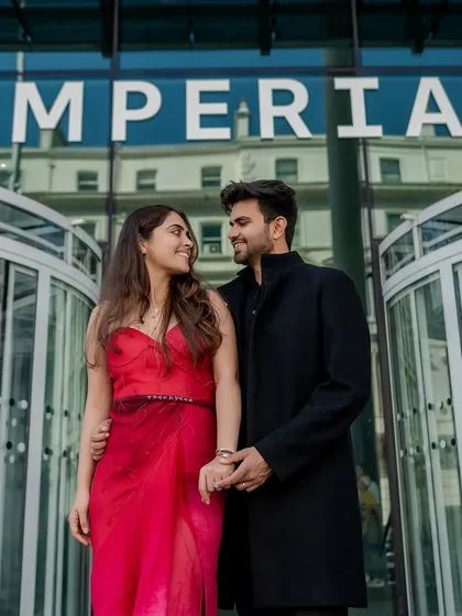 A chic, urban portrait in front of the Imperial College building in London. The couple's all-black and red outfits create a sophisticated look that is perfect for a city pre-wedding shoot.
