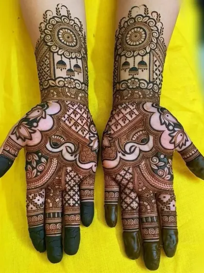 This design features traditional jhumka (earring) motifs and mandalas on the back of the hands. The palms are filled with classic checkerboard and paisley patterns, creating a full and festive look.