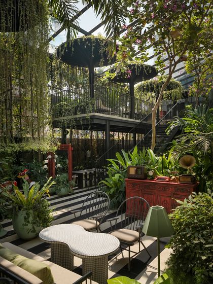 Here, vintage objects like a gramophone and a red cabinet are placed within the lush greenery, adding a layer of retro storytelling. This juxtaposition of curated objects and wild planting creates unique, explorable moments throughout the restaurant space.