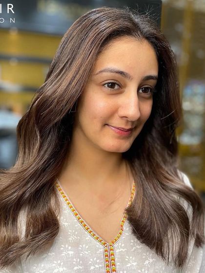 A happy client showing off her new balayage. The soft, natural-looking highlights give her a beautiful, sun-kissed glow.