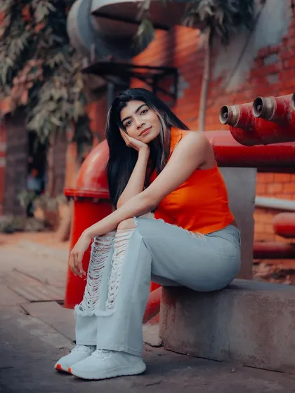 An industrial setting with red pipes provides a great contrast for this portrait. The model's relaxed pose and the vibrant colors create a strong urban fashion image.