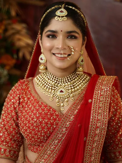 A happy, smiling portrait of a bride in her traditional red attire. The makeup is my signature style: subtle, glowing skin with sparkly eyes that light up her entire face.