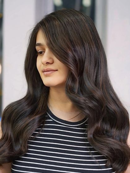 A side view of the long, wavy brunette style, showcasing the beautiful color blend and healthy, flowing locks.