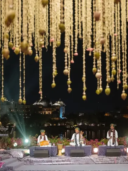 A live classical music performance on a stage set against the glittering Udaipur city palace at night. We curate world-class entertainment that complements the destination and enhances the overall guest experience.