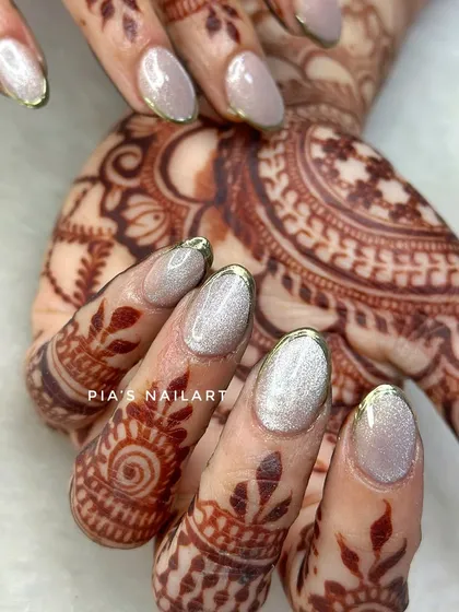 Short, sweet, and so elegant. These oval-shaped cat eye nails with a thin gold chrome French tip are perfect for any pre-wedding event.