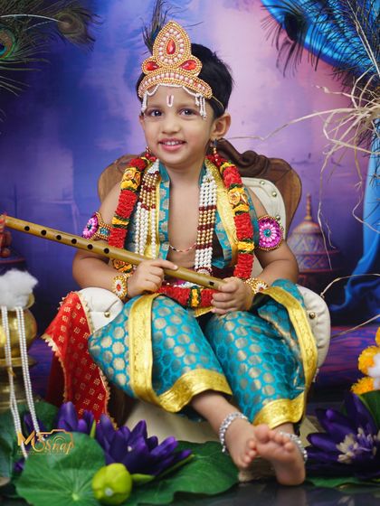 Another beautiful shot of our 'Little Krishna' seated gracefully among traditional props. This theme is a wonderful way to celebrate our culture.