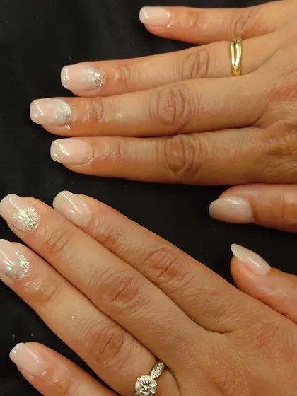 A very soft and elegant look perfect for any special occasion. These are natural-looking nude nails with a subtle silver glitter heart design on the ring fingers.