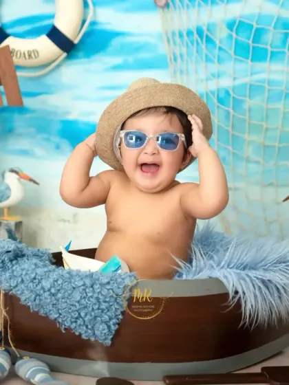 This 'Beach Baby' is having a great time, laughing with his sunglasses on while sitting in a boat prop.