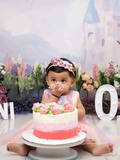 A taste of birthday magic! This little girl, dressed as a princess in a fairytale setting, gets her first taste of cake, a perfect moment captured during her "One" year photoshoot.
