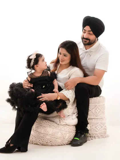 A stylish family portrait against a clean white background. The family's black and white attire creates a striking, high-contrast look that is both modern and timeless.