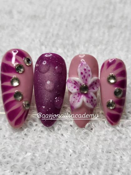 This design showcases a variety of techniques. It includes a 3D sculpted orchid, a magnetic cat-eye effect with water droplets, and a striped pattern with rhinestones.