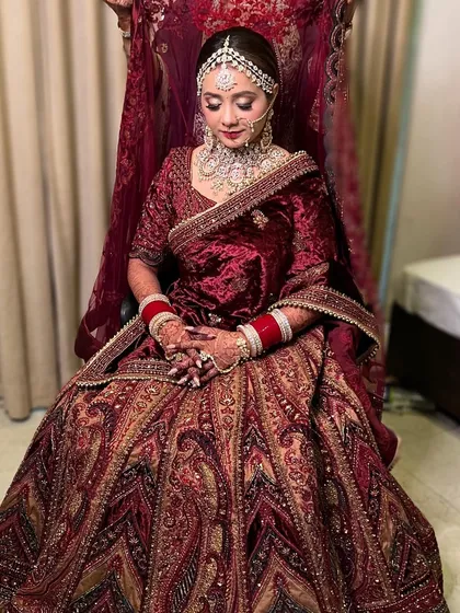 The full regal look. This bride is seated, showcasing her magnificent velvet lehenga and the complete bridal styling, from makeup to dupatta setting.
