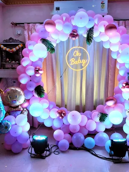 Perfect for intimate home celebrations, this baby shower decoration features a full circular balloon arch in pastel pink and purple. The glowing 'Oh Baby' neon sign at the center creates a warm and inviting focal point for your special day.