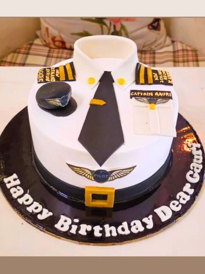 A sharp and detailed pilot uniform cake, complete with a hat, tie, and captain's insignia for a pilot's birthday.