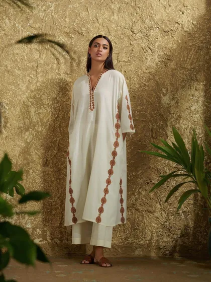 An example of tropical Indo-fusion. This white kurta with brown embroidered details offers a relaxed yet chic aesthetic, perfect for sophisticated daywear.
