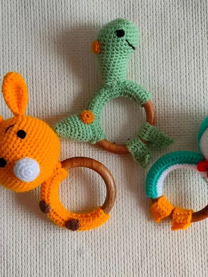 New rattle toy designs, including a giraffe, a dinosaur, and a sleeping penguin. They make a gentle sound that babies love.