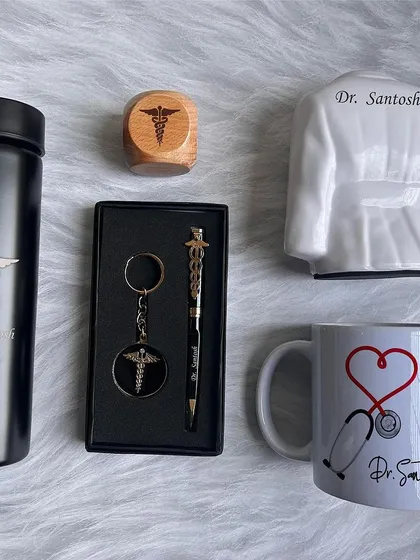This Doctor Combo 2.0 is a perfect gift for medical professionals. It includes a turbo bottle, pen, keychain, a doctor's coat pen stand, a ceramic mug, and a wooden paperweight, all customizable.